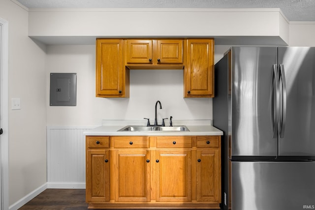 kitchen with freestanding refrigerator, electric panel, dark wood-style flooring, a sink, and brown cabinets