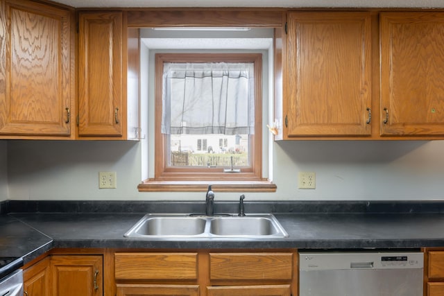 kitchen with dark countertops, brown cabinets, a sink, and stainless steel appliances