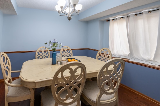 dining space featuring baseboards, a notable chandelier, and wood finished floors