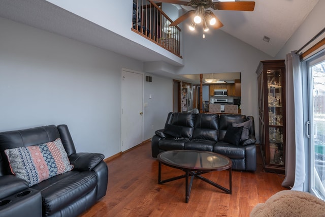 living area with wood finished floors, ceiling fan, visible vents, and high vaulted ceiling