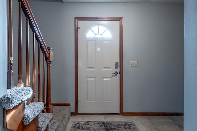 entryway with stairway, baseboards, and light tile patterned flooring