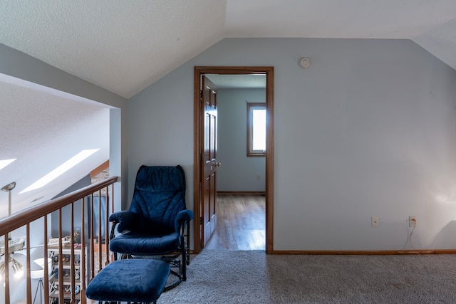 sitting room with vaulted ceiling with skylight, a textured ceiling, baseboards, and carpet floors