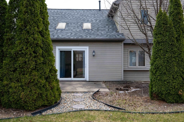 back of property with a patio and a shingled roof
