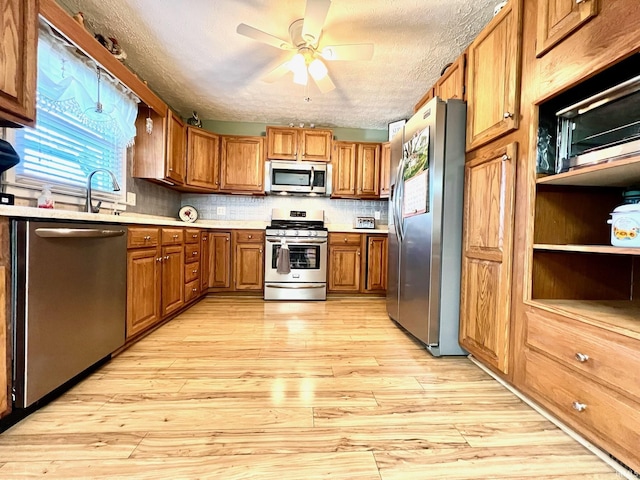 2119 Windwood Dr, Bedford, IN 47421 - kitchen featuring light wood-style flooring, light countertops, brown cabinetry, ceiling fan, and stainless steel appliances