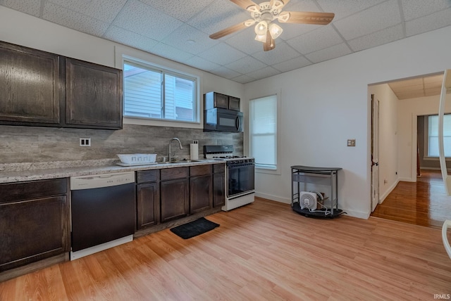 kitchen featuring white gas stove, black microwave, dishwashing machine, a drop ceiling, and a sink