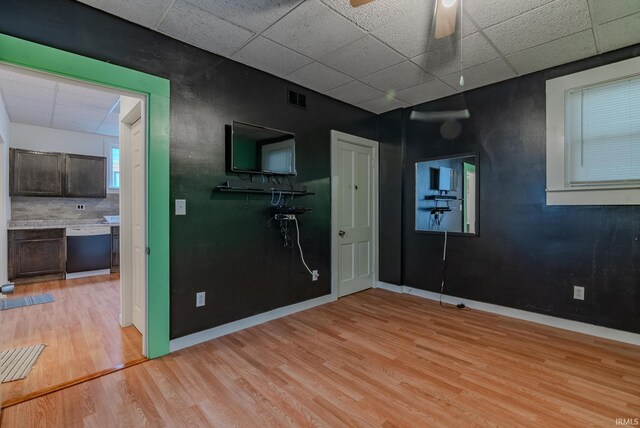 unfurnished room featuring ceiling fan, a drop ceiling, visible vents, light wood finished floors, and baseboards