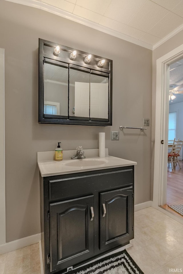 bathroom with tile patterned floors, vanity, baseboards, and ornamental molding