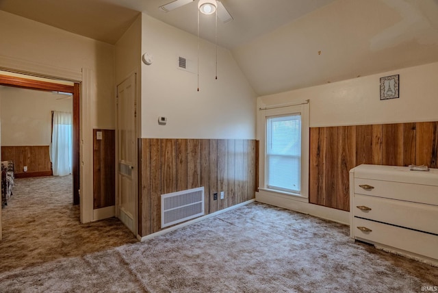 unfurnished bedroom featuring visible vents, a wainscoted wall, carpet flooring, and wood walls