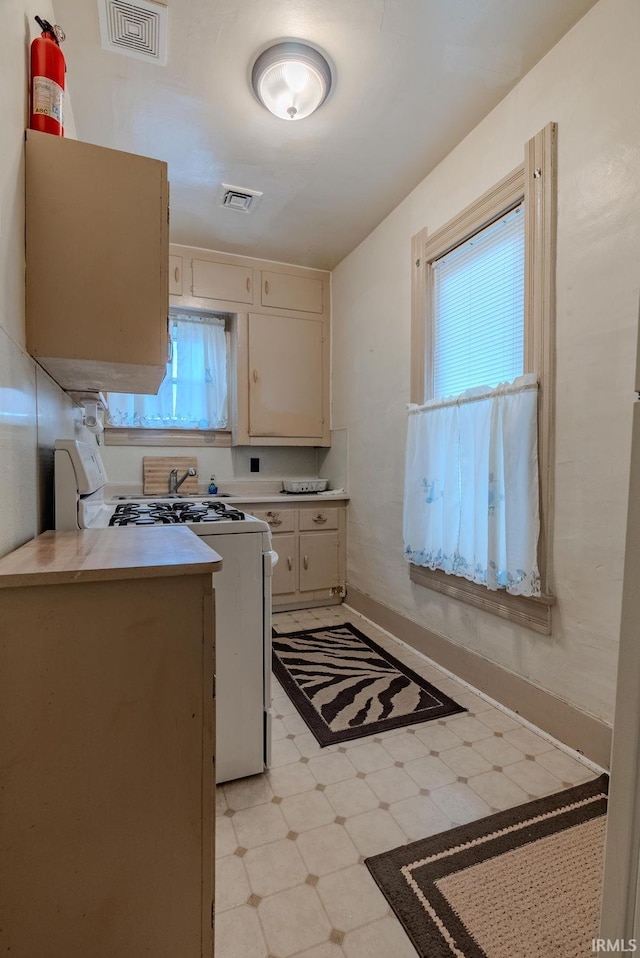 kitchen with gas range oven, light countertops, visible vents, and light floors