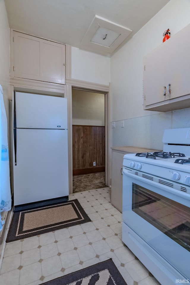 kitchen with white appliances, light countertops, white cabinets, under cabinet range hood, and light floors