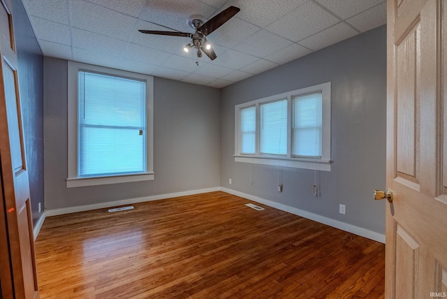 spare room with visible vents, a ceiling fan, a drop ceiling, and wood finished floors