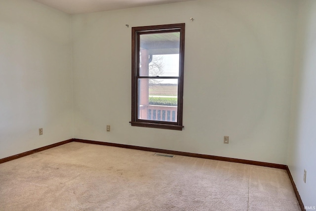 empty room with visible vents, light colored carpet, and baseboards