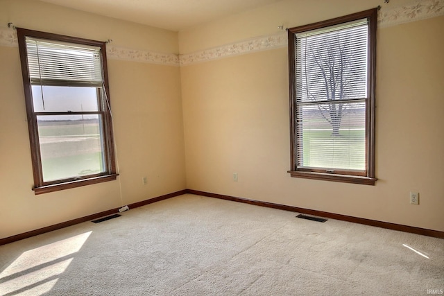 empty room featuring a wealth of natural light, carpet, and visible vents