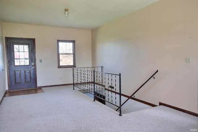 entryway with baseboards and carpet