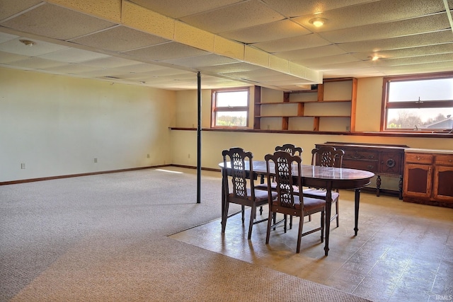 dining area featuring baseboards, a paneled ceiling, and light carpet