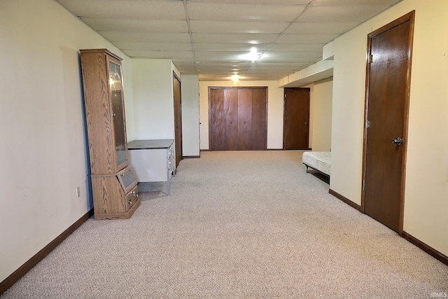 hallway with light carpet, baseboards, and a drop ceiling