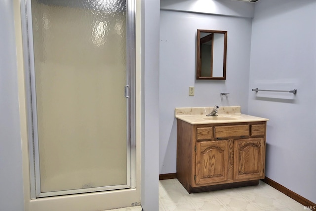bathroom with a stall shower, vanity, and baseboards