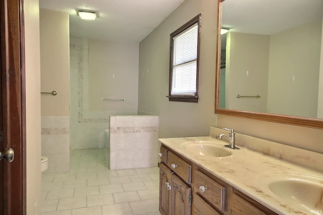 full bathroom with toilet, tile patterned floors, double vanity, and a sink