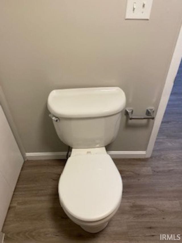bathroom featuring toilet, wood finished floors, and baseboards