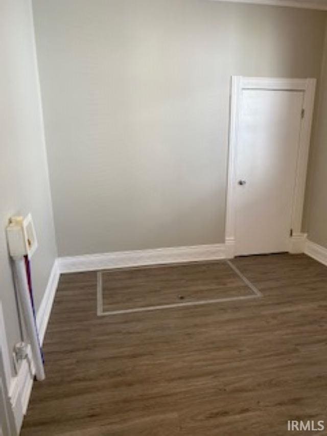 spare room featuring dark wood-style flooring and baseboards