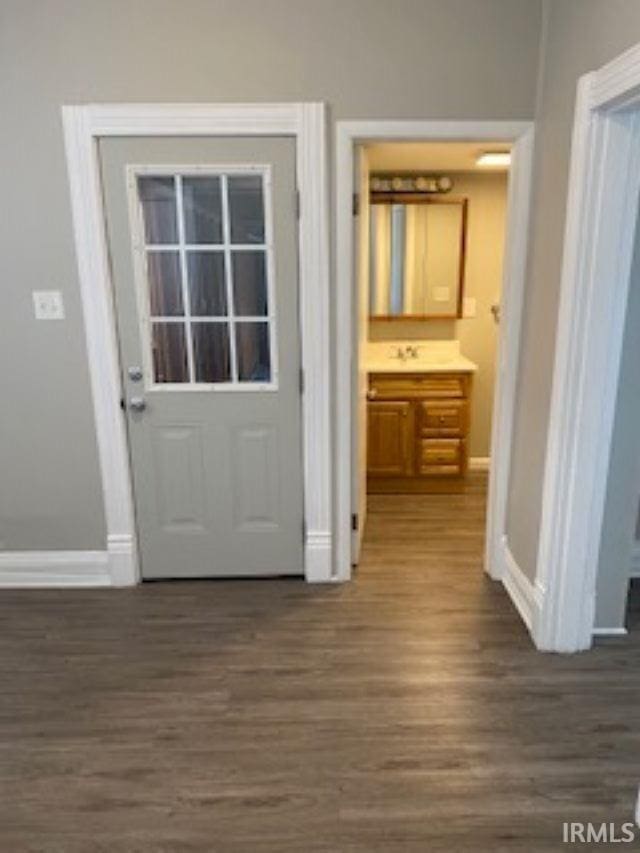 entryway with dark wood-type flooring and baseboards
