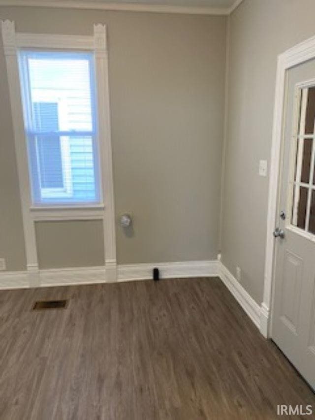 unfurnished room with crown molding, visible vents, baseboards, and wood finished floors
