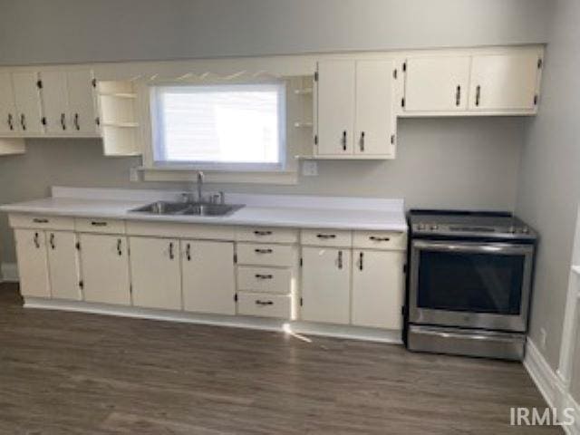 kitchen featuring dark wood-type flooring, stainless steel electric range oven, a sink, and open shelves