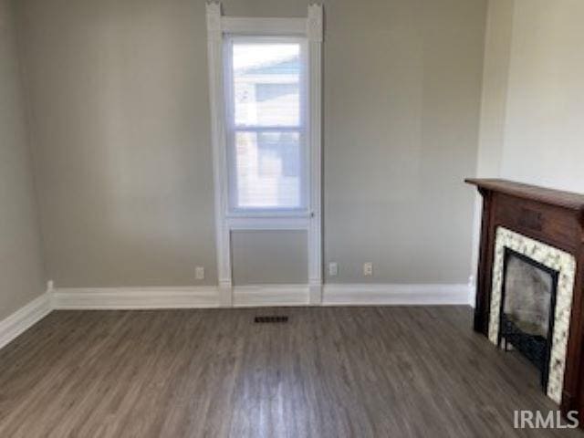 unfurnished living room with plenty of natural light, a fireplace, baseboards, and wood finished floors