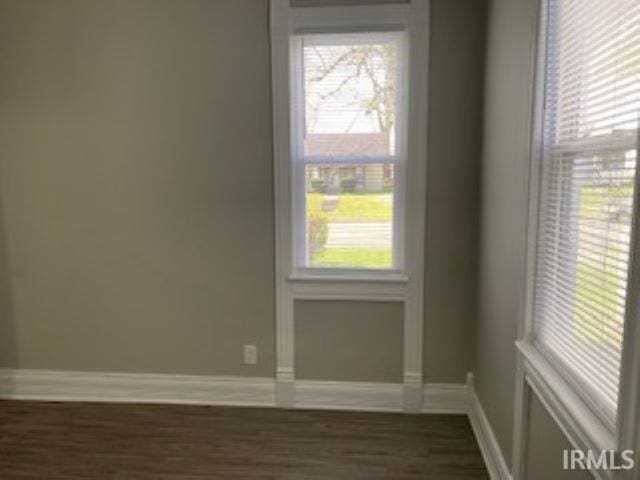 unfurnished room with dark wood-style flooring, baseboards, and plenty of natural light