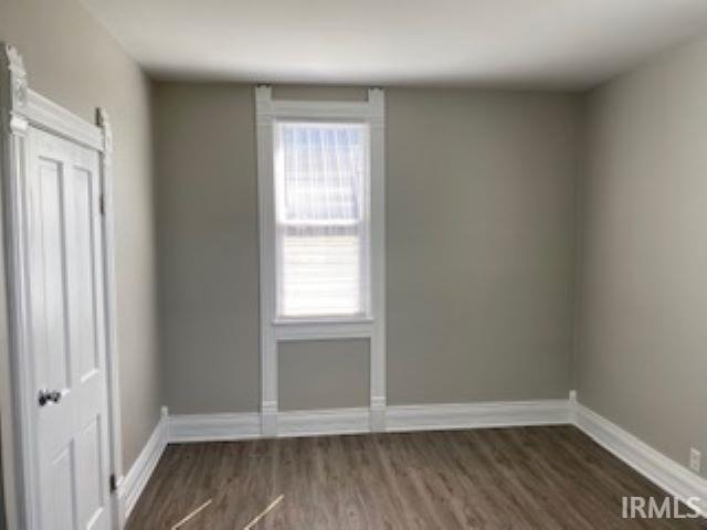 empty room featuring dark wood-style flooring and baseboards
