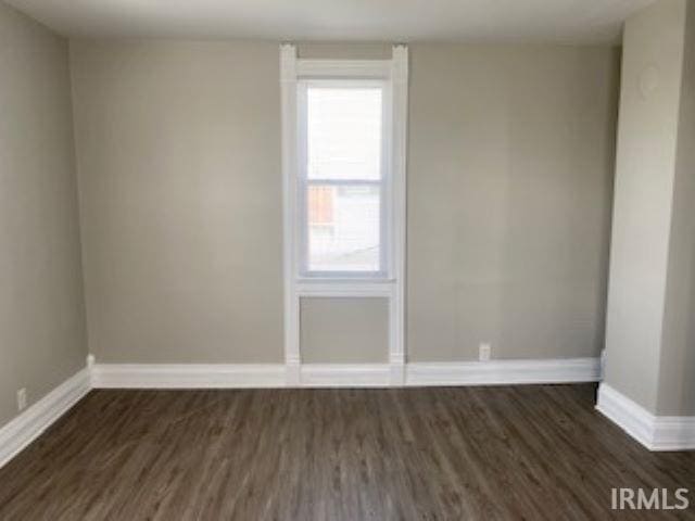 spare room featuring dark wood-style flooring and baseboards
