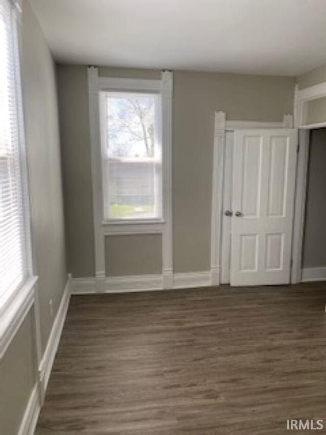 unfurnished room featuring dark wood-type flooring and baseboards