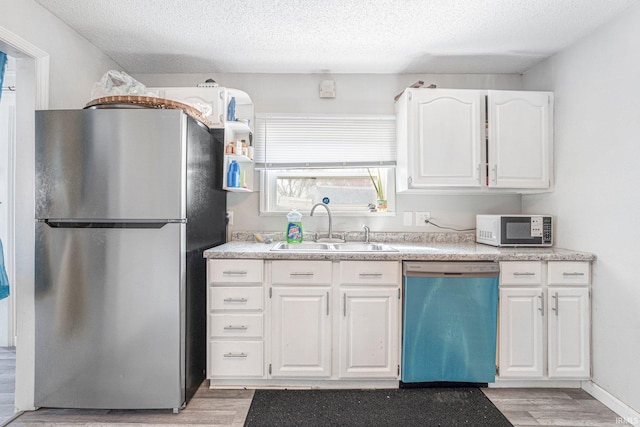3930 Abbott St, Fort Wayne, IN 46806 - kitchen featuring white microwave, freestanding refrigerator, light wood-style floors, dishwasher, and a sink