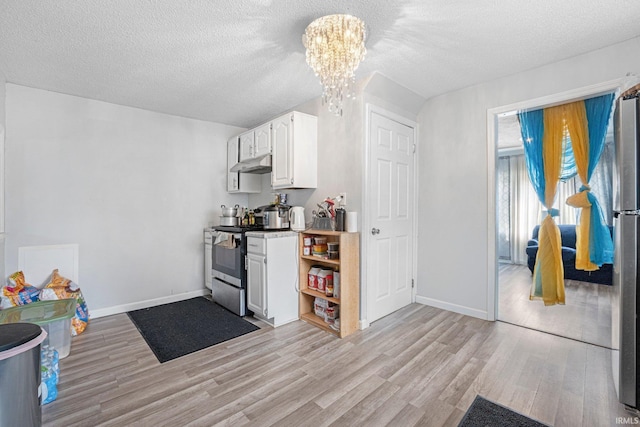 3930 Abbott St, Fort Wayne, IN 46806 - kitchen with under cabinet range hood, light wood finished floors, an inviting chandelier, and appliances with stainless steel finishes
