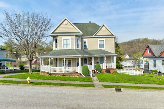victorian-style house with a front lawn, covered porch, and roof with shingles