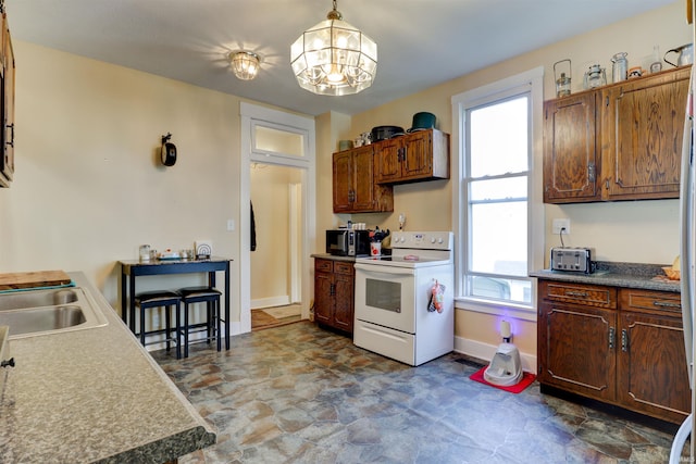 kitchen featuring baseboards, an inviting chandelier, white electric stove, stone finish flooring, and pendant lighting