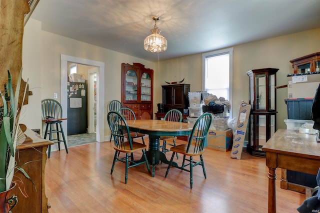 dining space with light wood-style flooring and a notable chandelier