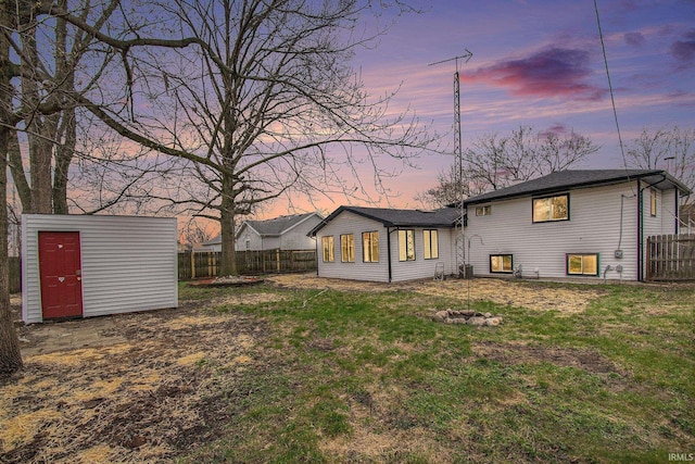 214 Parkwood Ln, South Bend, IN 46619 - back of house at dusk with a storage shed, an outdoor structure, a lawn, and fence private yard