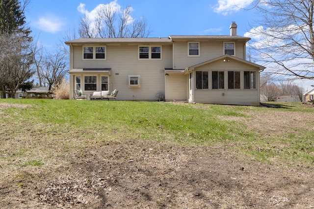 rear view of property featuring a lawn, a chimney, and a sunroom