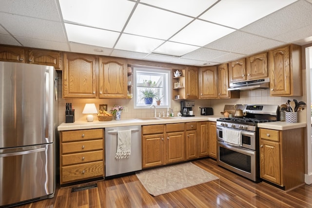 kitchen featuring stainless steel appliances, a sink, open shelves, under cabinet range hood, and dark wood-type flooring