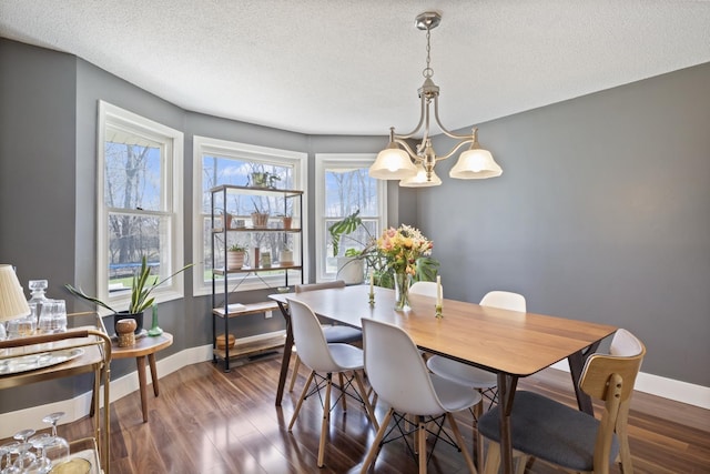 dining area with baseboards, a chandelier, wood finished floors, and a textured ceiling