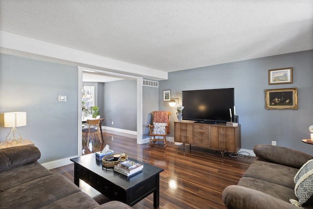 living room featuring baseboards, wood finished floors, visible vents, and a textured ceiling