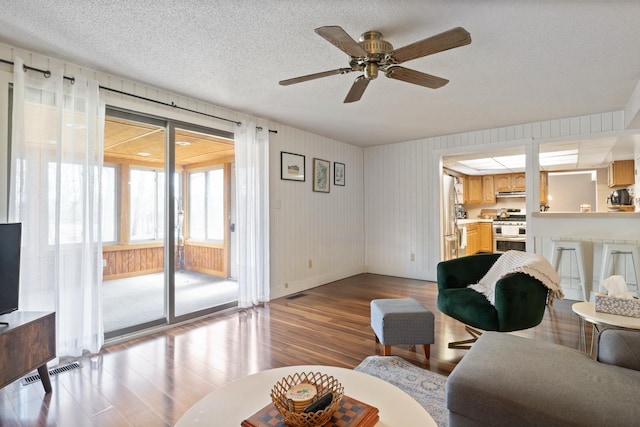 living area with wood finished floors, visible vents, baseboards, a textured ceiling, and ceiling fan