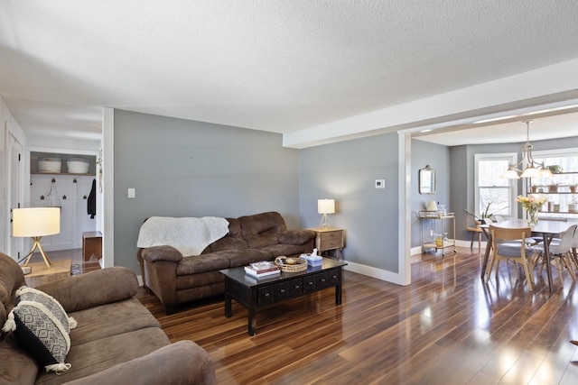 living area with baseboards, wood finished floors, a textured ceiling, and a notable chandelier