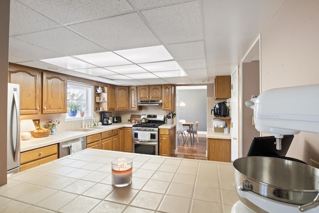 kitchen with stainless steel appliances, a sink, open shelves, brown cabinetry, and under cabinet range hood