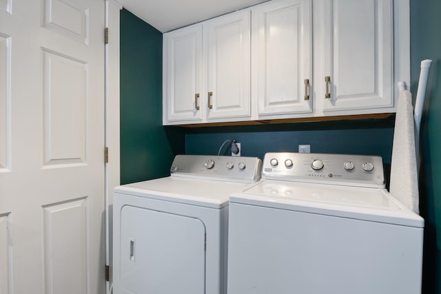 clothes washing area featuring washing machine and clothes dryer and cabinet space