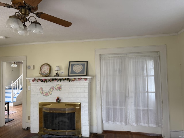 living room featuring crown molding, wood finished floors, a brick fireplace, and a ceiling fan
