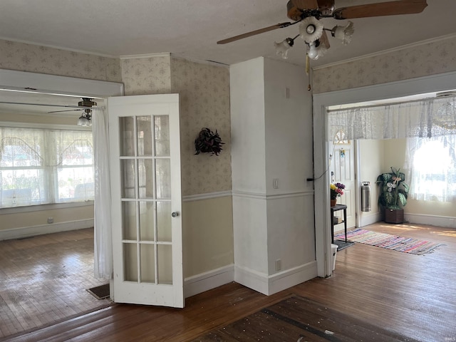 interior space featuring wallpapered walls, hardwood / wood-style floors, a healthy amount of sunlight, and baseboards