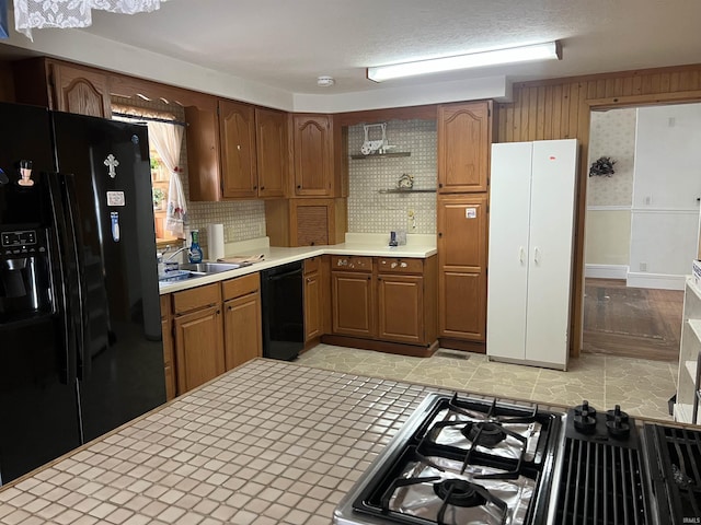 kitchen with open shelves, brown cabinets, a sink, and black appliances
