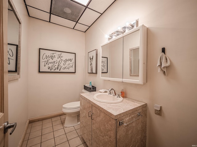 8901 Vienna Rd, Evansville, IN 47720 - half bathroom featuring tile patterned flooring, toilet, vanity, baseboards, and a paneled ceiling